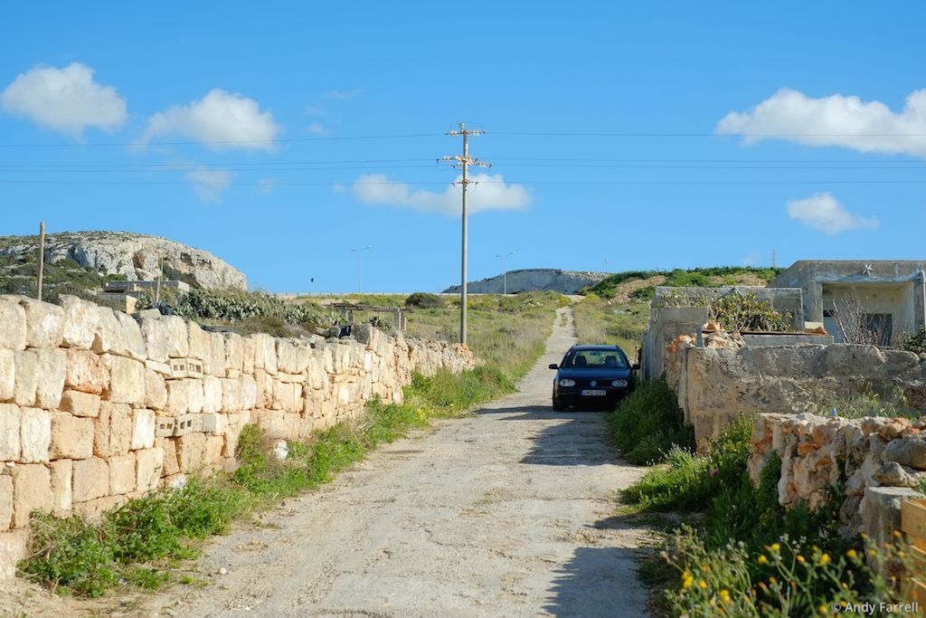side road leading up a hill, with parked car