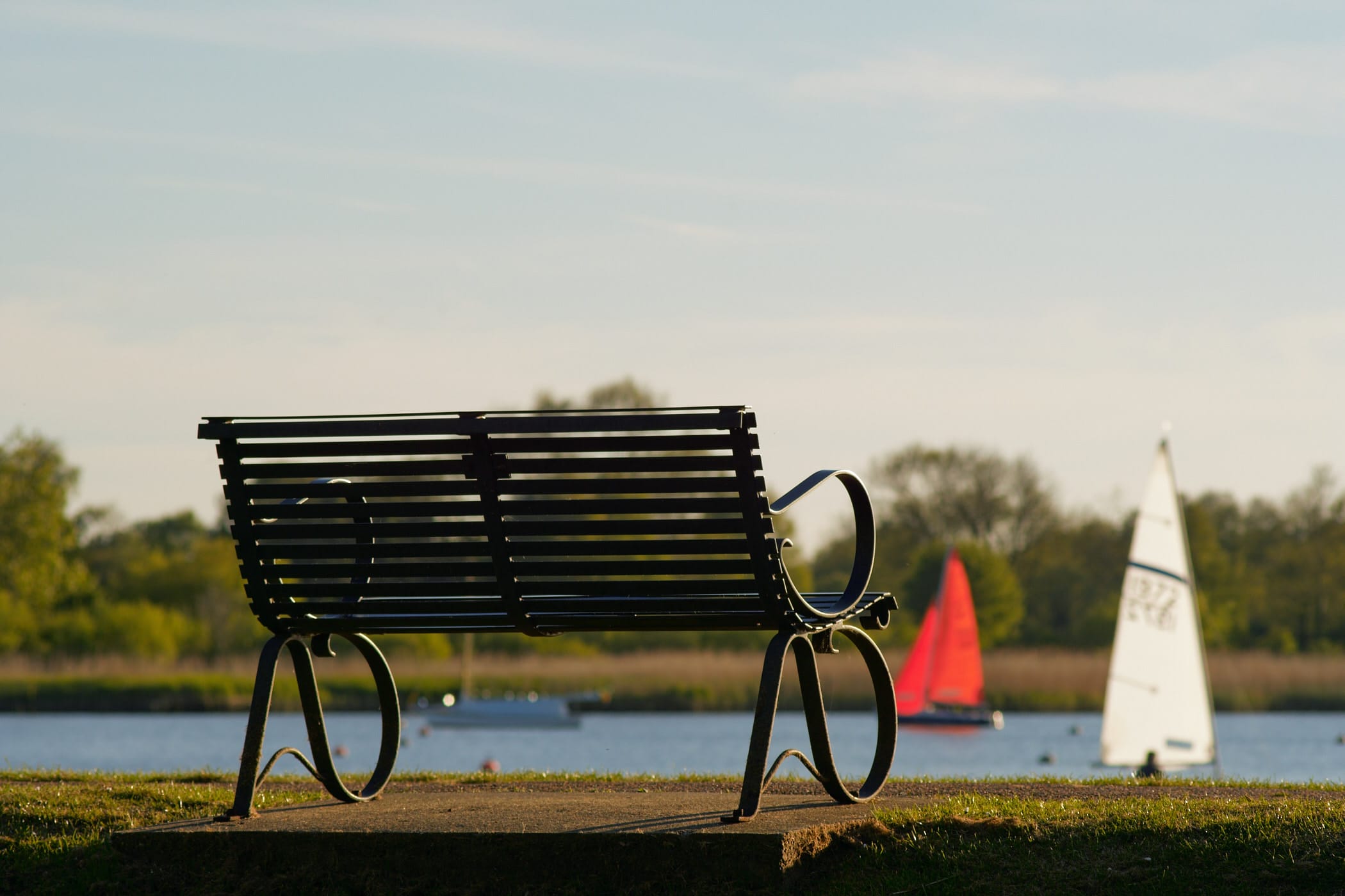 park bench with sailing dinghies in the background