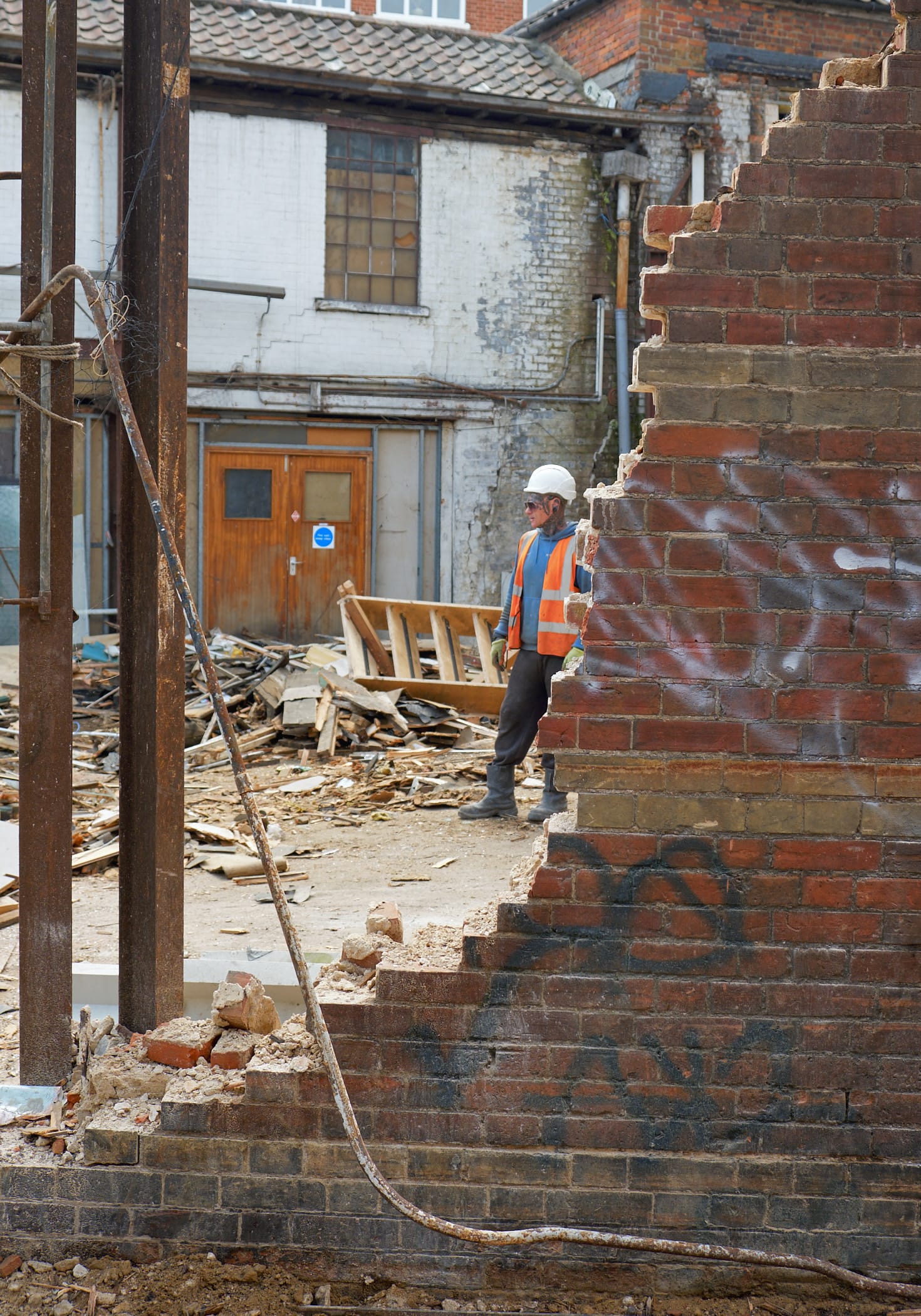 workman behind partially demolished wall