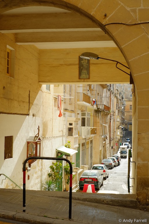 looking out onto a sunlit road from a shaded archway