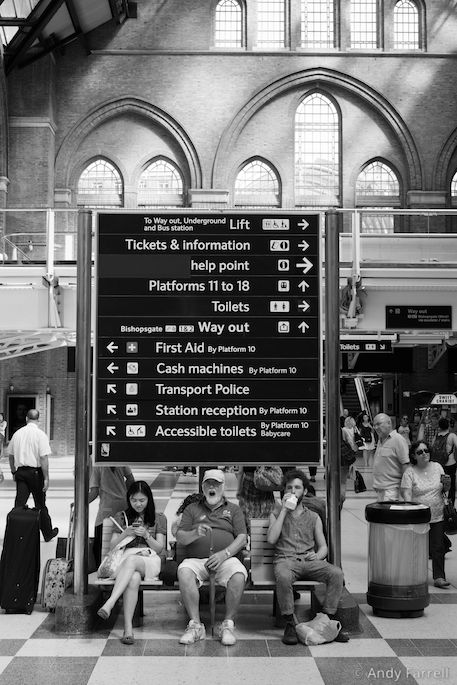 people waiting in Liverpool Street station beneath an information sign