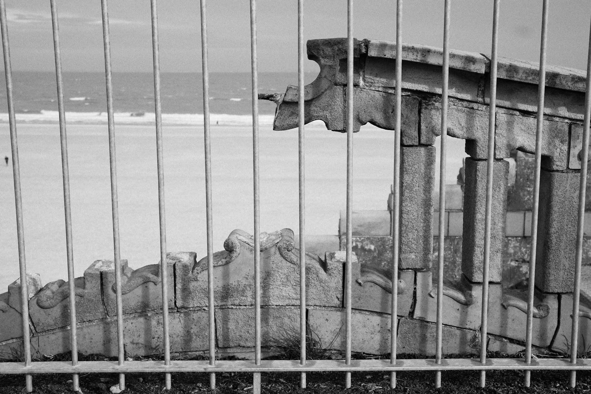 broken stone wall behind metal railing