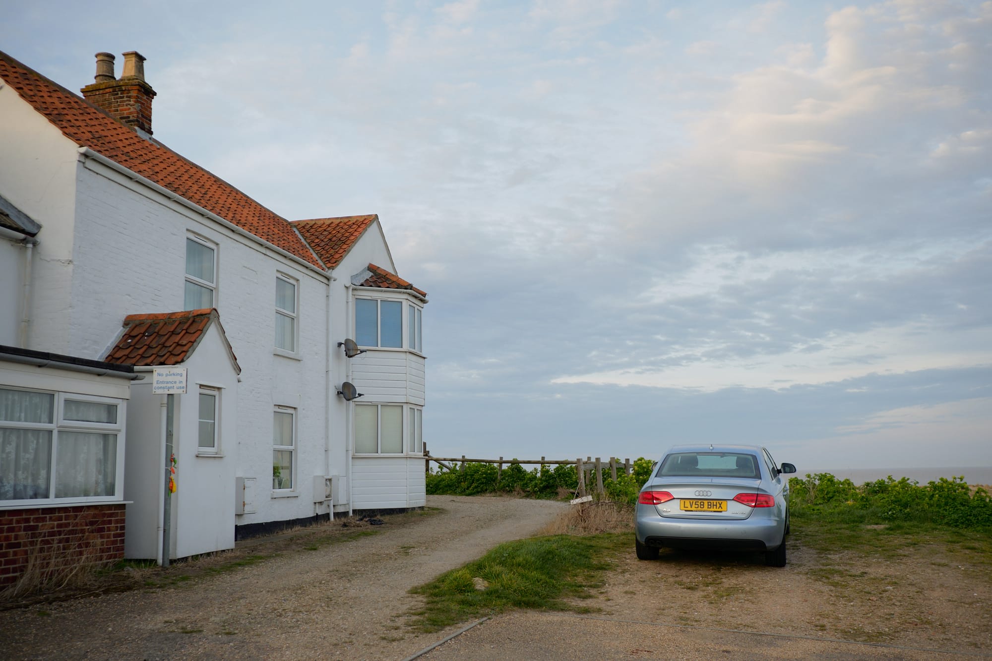 car parked by a house overlooking the beach