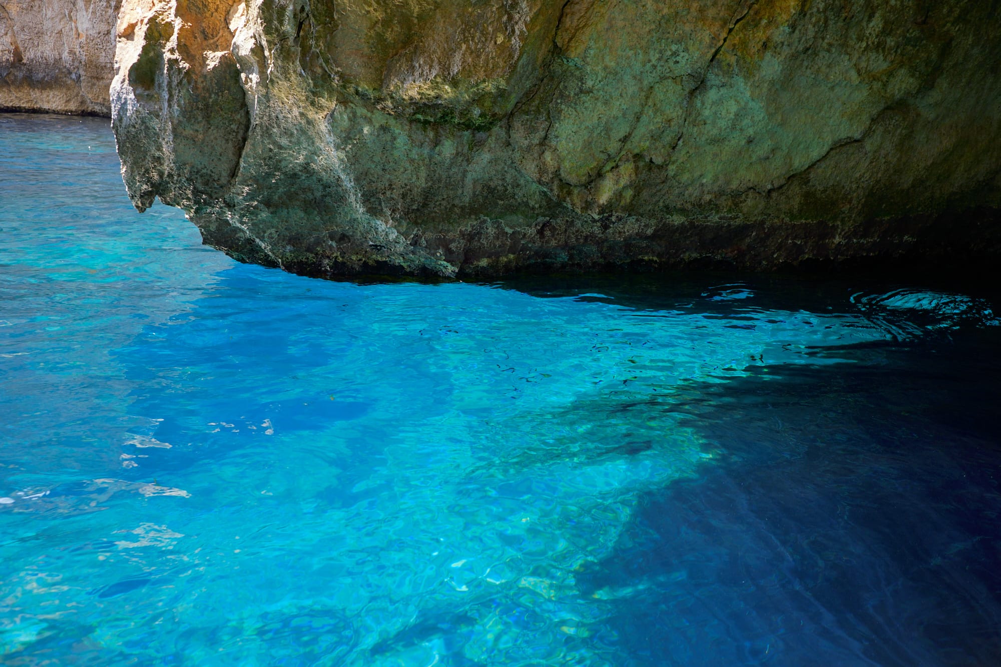 rock overhanging blue water