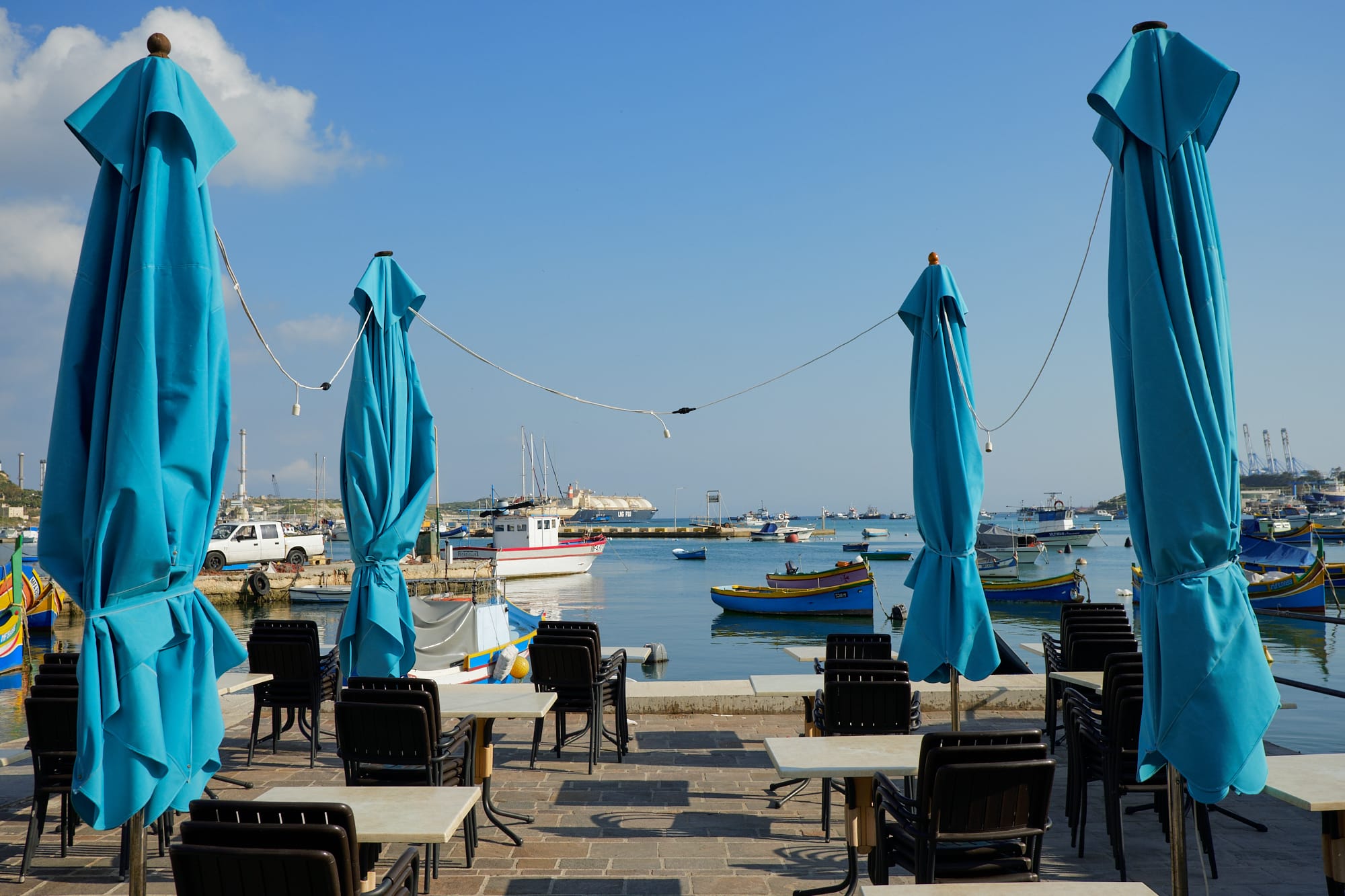 stowed blue sunshades and outdoor seating at a café