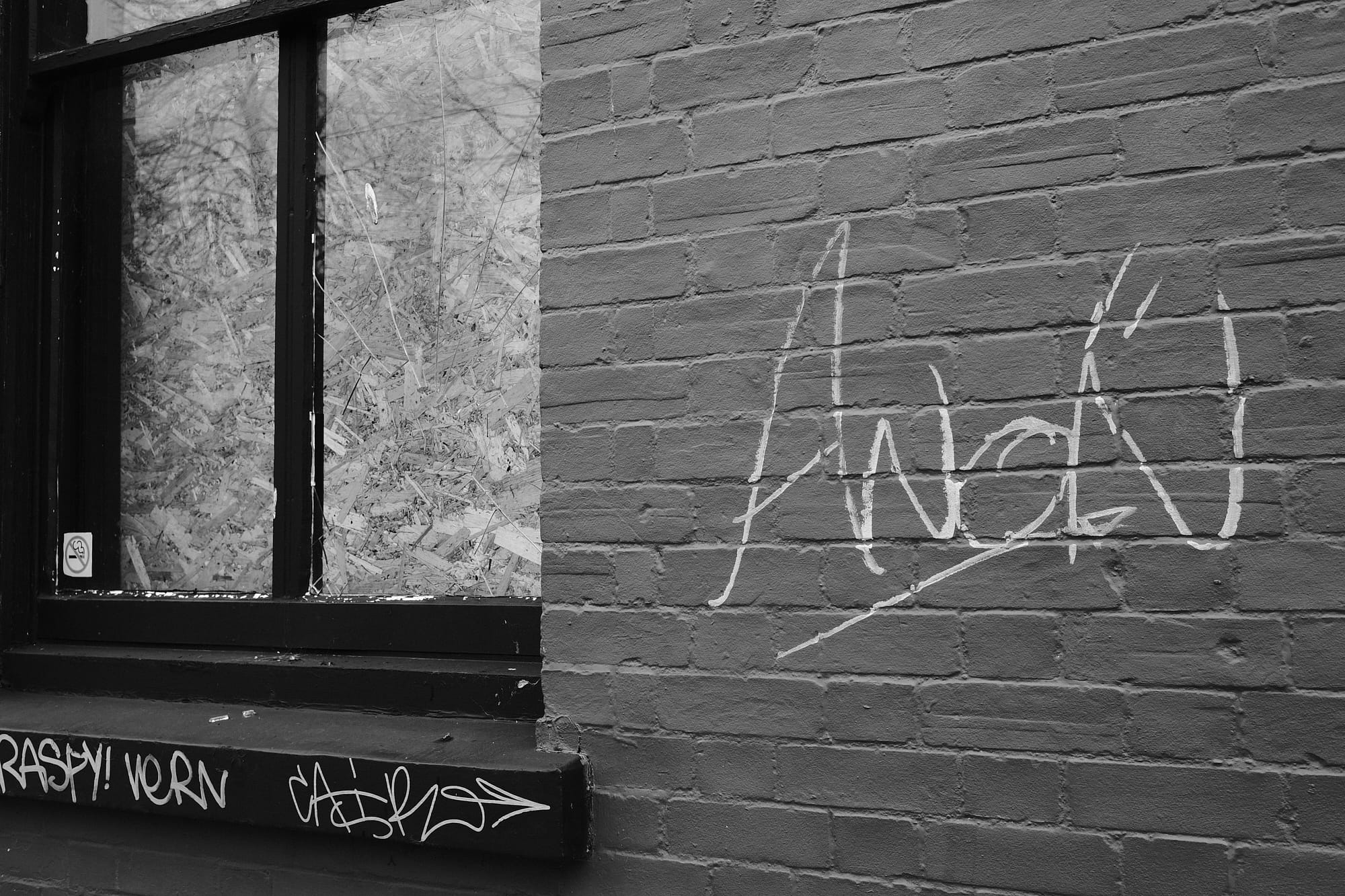boarded-up broken window and 'Anon' graffiti