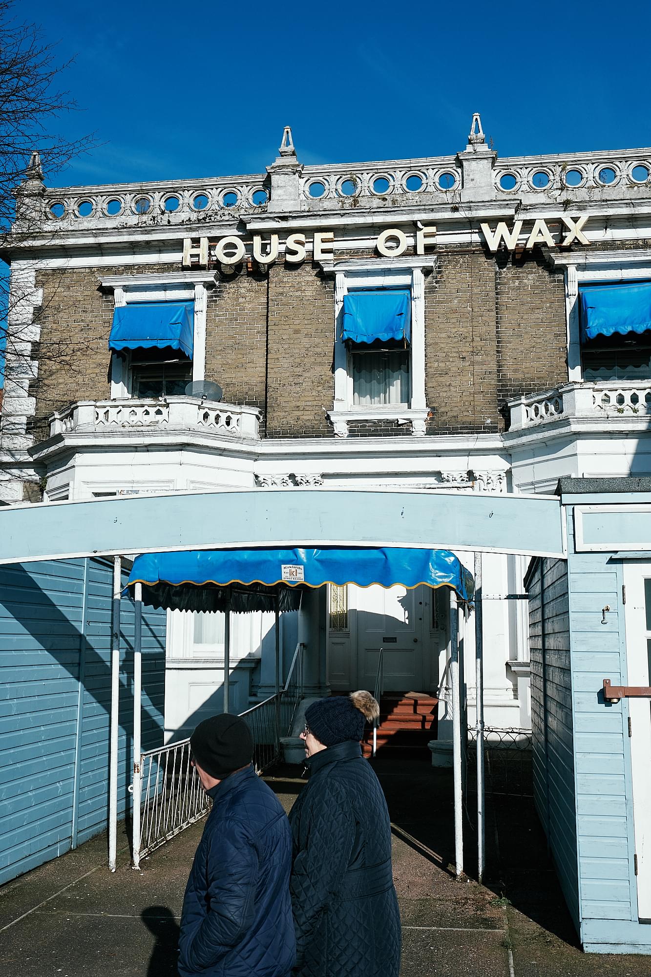 people walking past the entrance to House of Wax