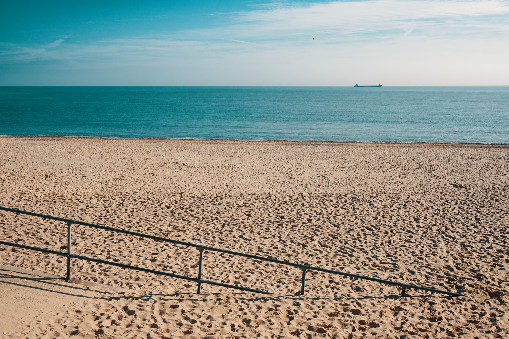 Lowestoft beach, with a railing disappearing into the sand