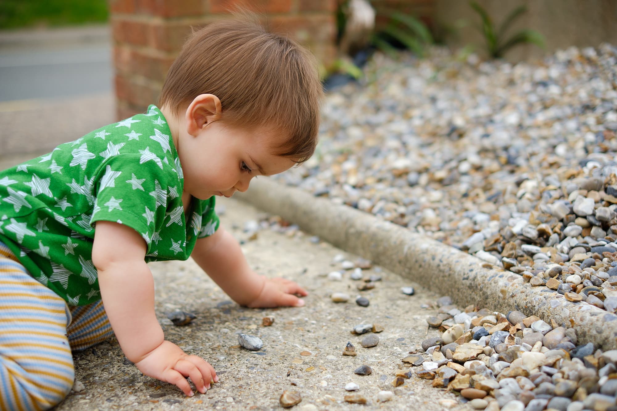 Em playing with stones in our driveway