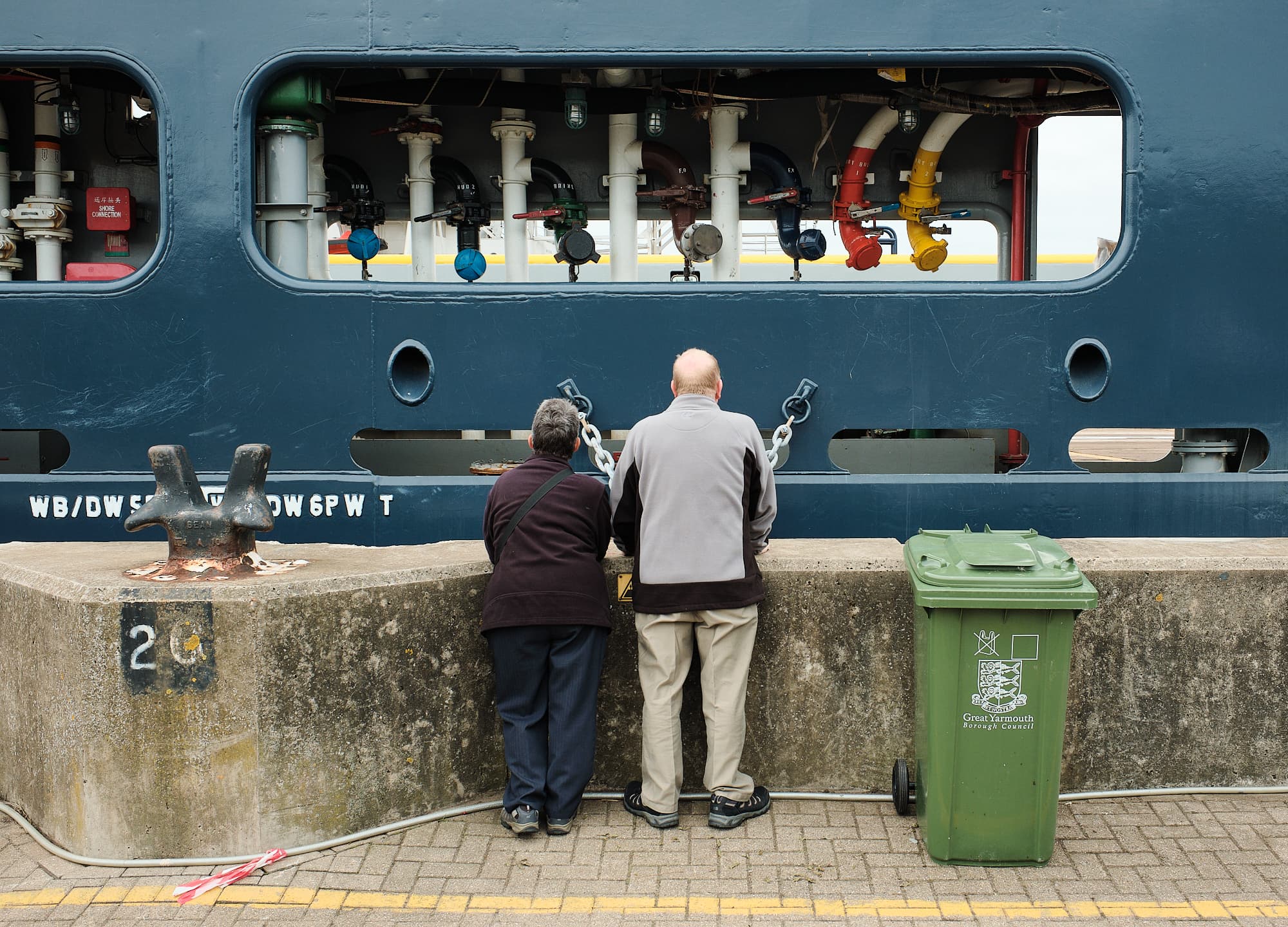couple looking at the assorted pipework of a container ship