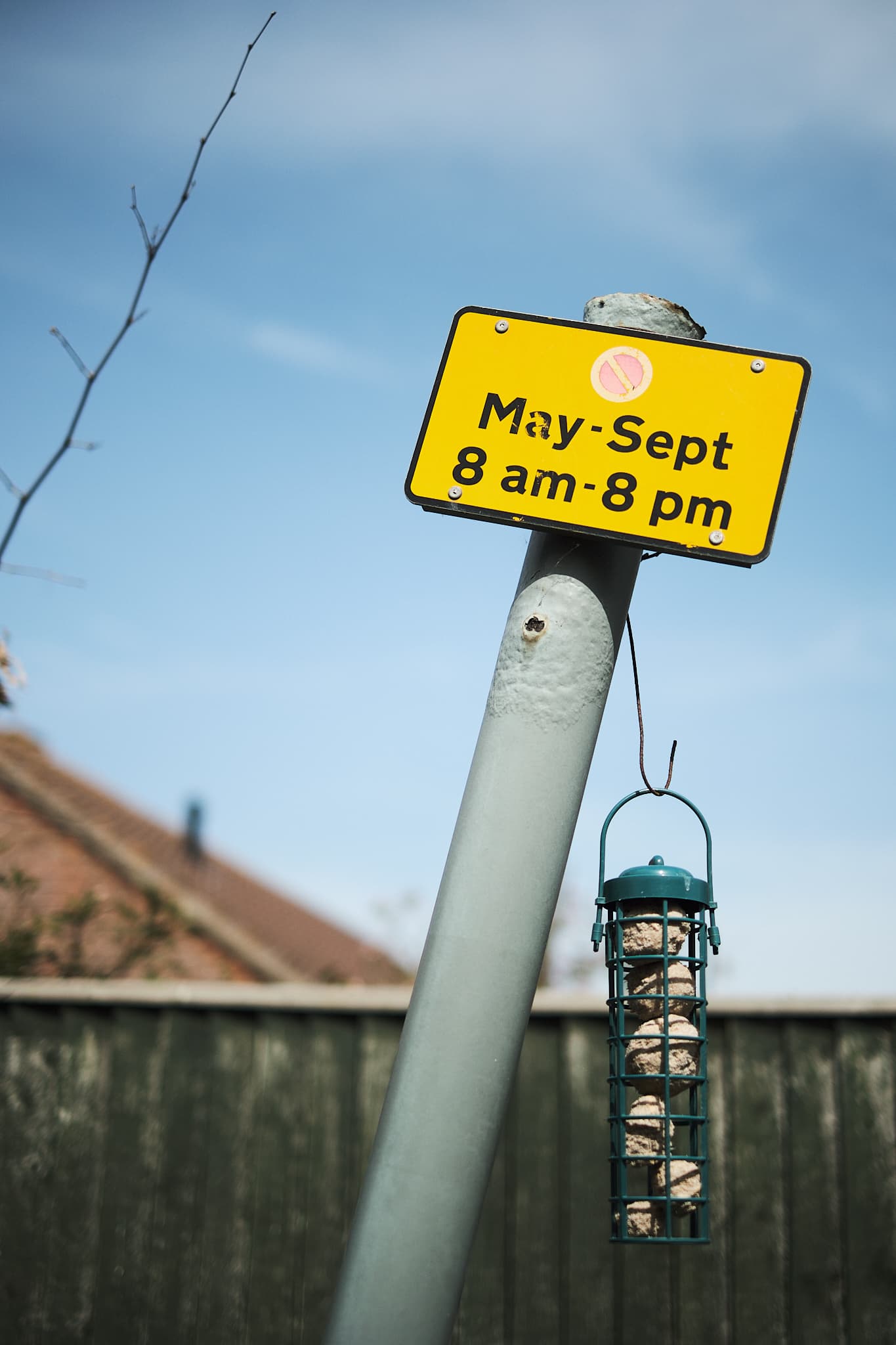 tilted sign with bird feeder hanging from it