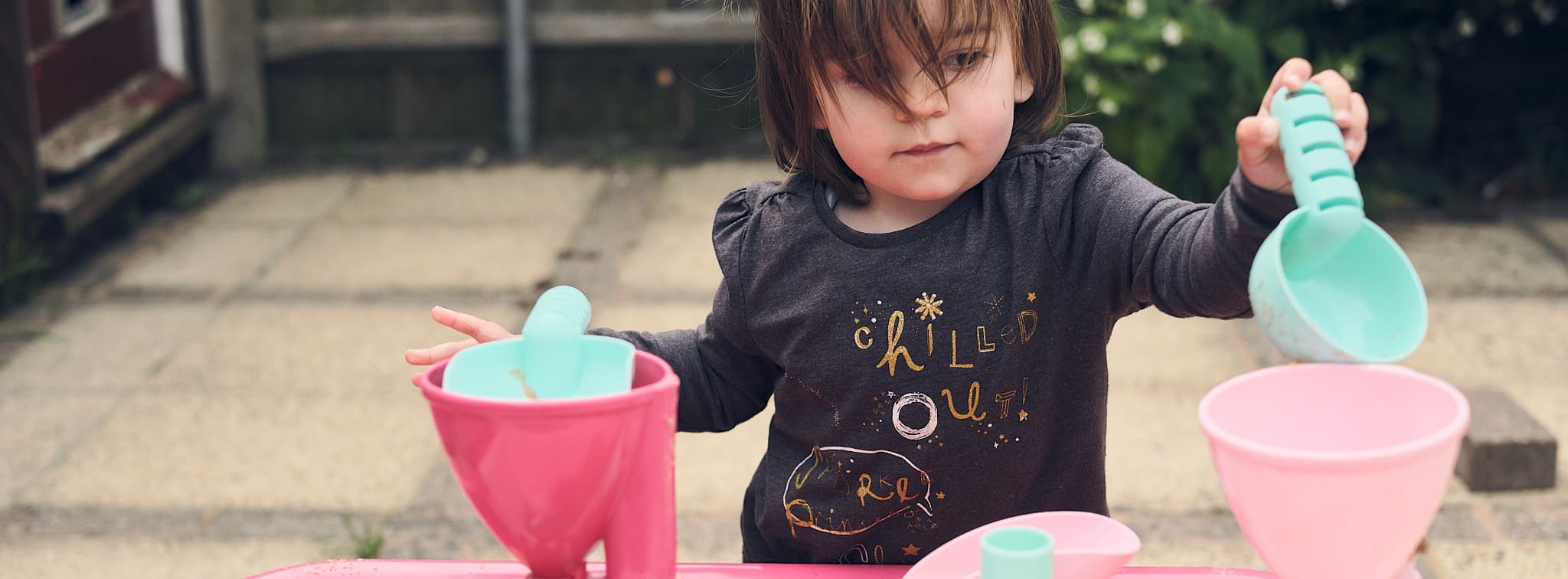 Emily playing thoughtfully with a sand/water toy