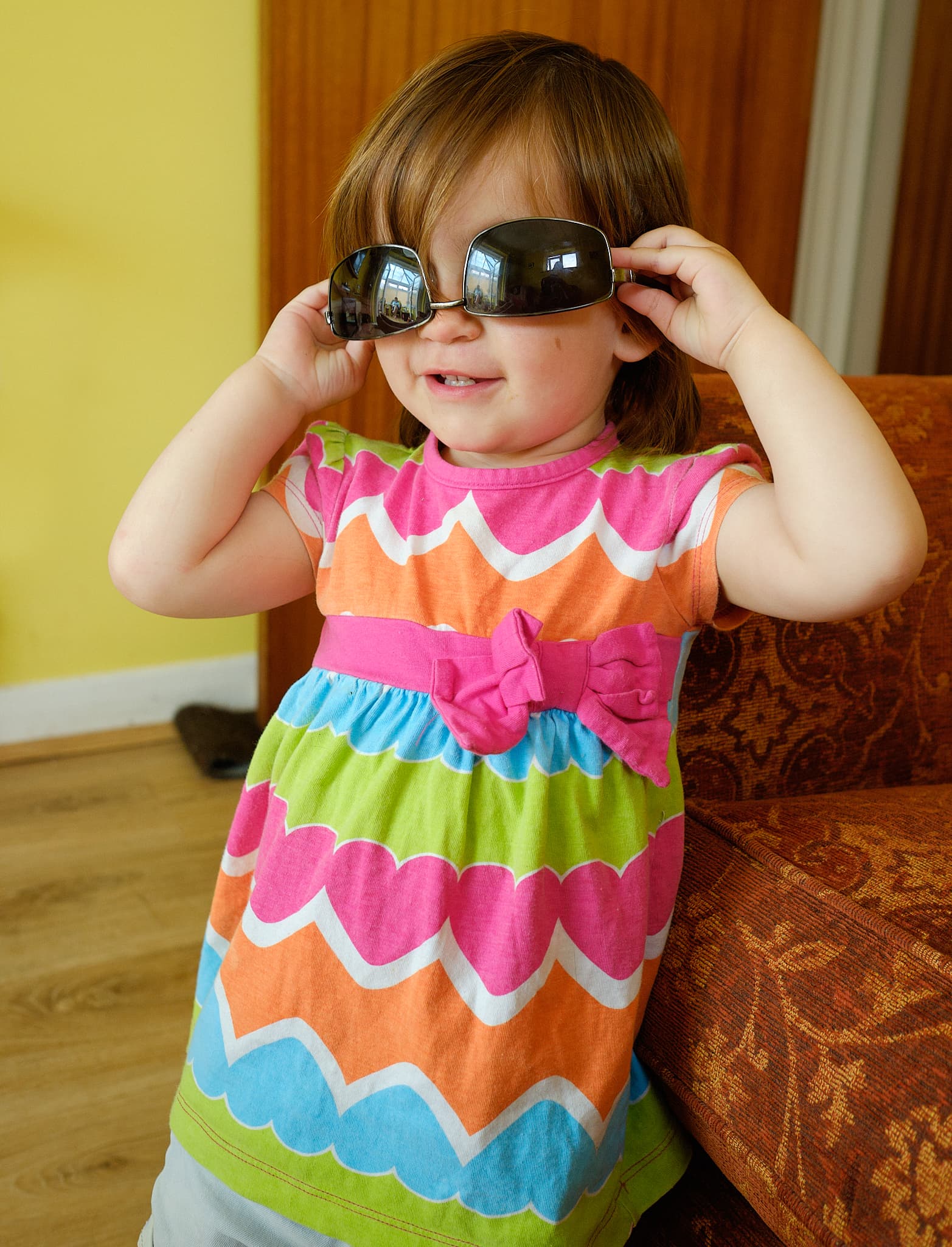 Emily in a rainbow dress trying on sunglasses